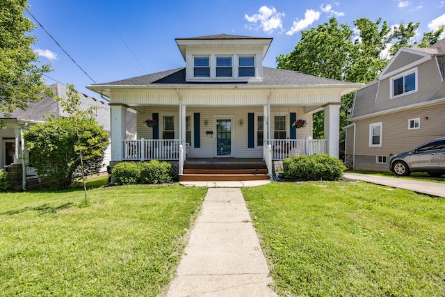 bungalow-style house featuring a front yard, covered porch, and roof with shingles