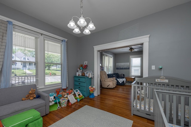 bedroom with a chandelier, wood finished floors, and a nursery area