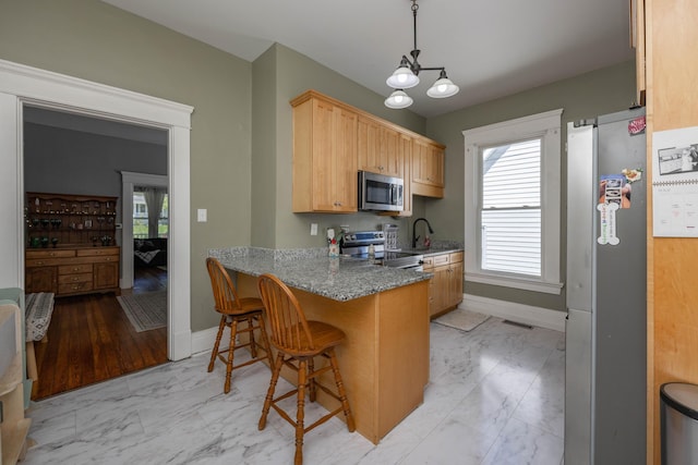 kitchen featuring stainless steel appliances, light marble finish flooring, baseboards, and a chandelier
