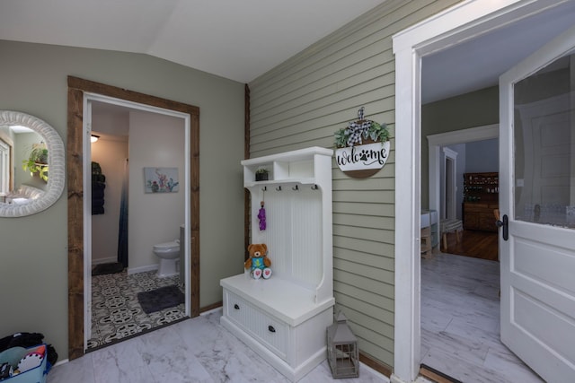 mudroom with lofted ceiling, wooden walls, and light marble finish flooring