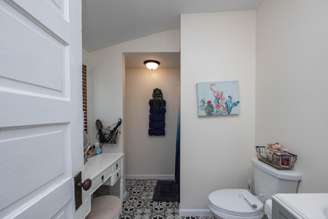 bathroom featuring toilet, vaulted ceiling, baseboards, and vanity