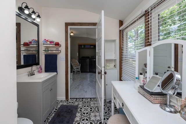 bathroom featuring lofted ceiling, vanity, baseboards, tile patterned flooring, and washer and dryer