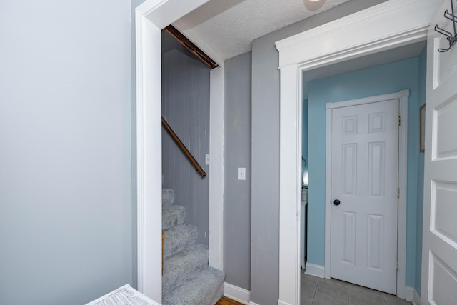 staircase with baseboards and tile patterned floors