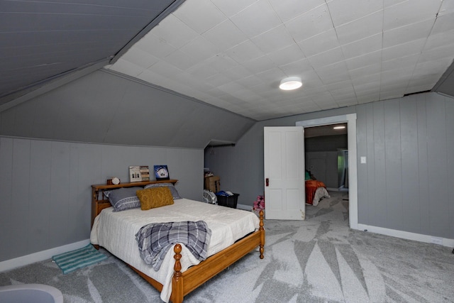 bedroom with vaulted ceiling, carpet floors, baseboards, and wooden walls