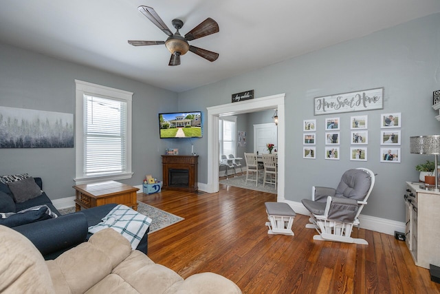 living room with baseboards, a ceiling fan, wood finished floors, and a fireplace