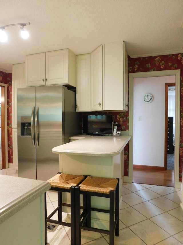 184 Meadow Dr, Harlan, KY 40831 - kitchen featuring stainless steel fridge, wallpapered walls, white cabinets, light countertops, and light tile patterned floors