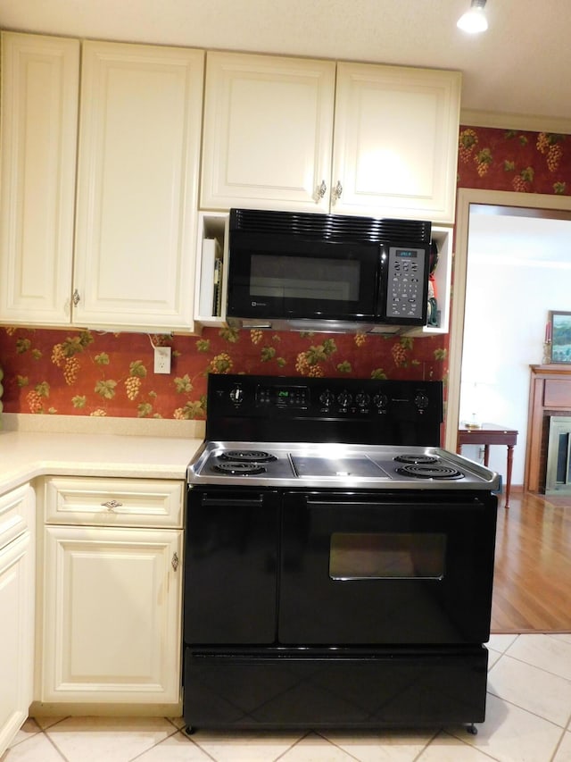 184 Meadow Dr, Harlan, KY 40831 - kitchen with black appliances, wallpapered walls, light countertops, light tile patterned floors, and cream cabinets