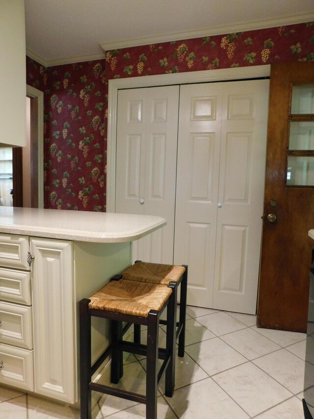 184 Meadow Dr, Harlan, KY 40831 - kitchen featuring crown molding, light countertops, wallpapered walls, light tile patterned flooring, and white cabinetry