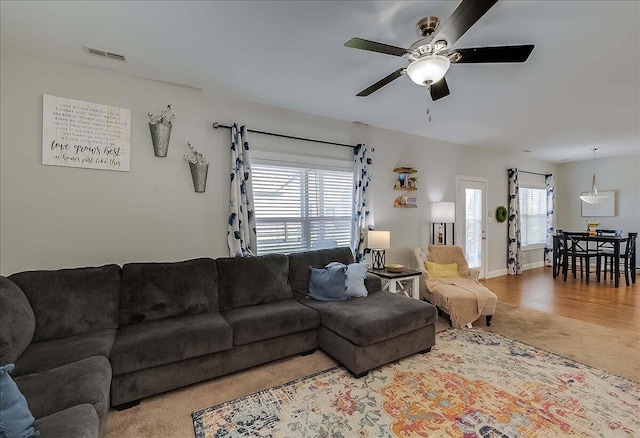 carpeted living room with ceiling fan and baseboards
