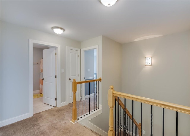 hallway with an upstairs landing, carpet floors, and baseboards