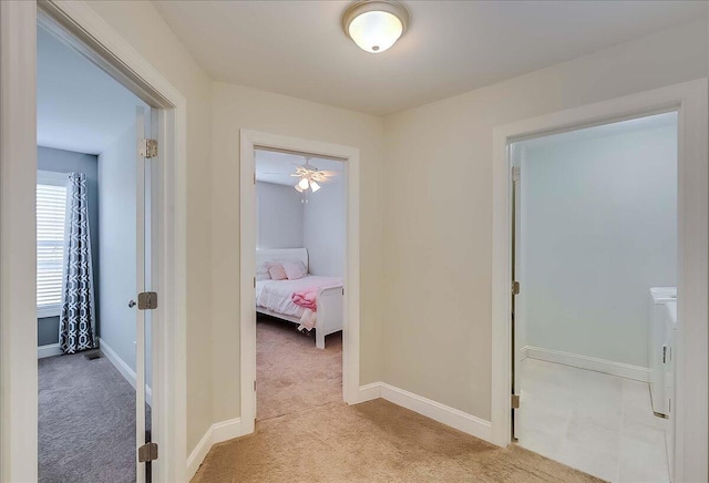 corridor featuring light colored carpet and baseboards