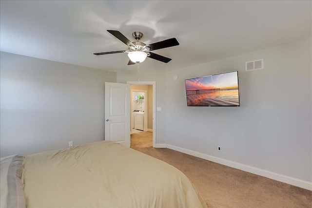 bedroom with light colored carpet, baseboards, washer / dryer, and a ceiling fan