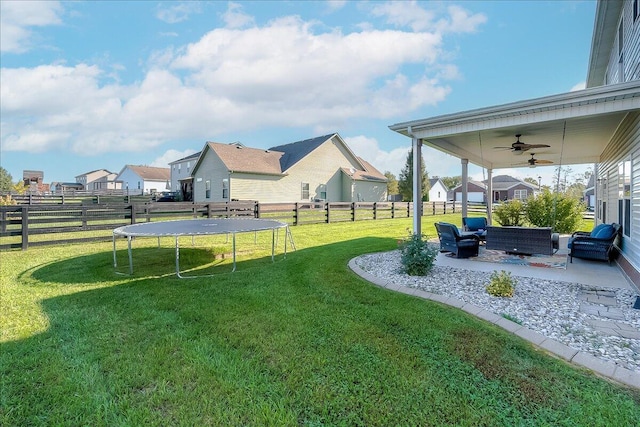 view of yard featuring a trampoline, an outdoor hangout area, ceiling fan, a patio area, and a residential view