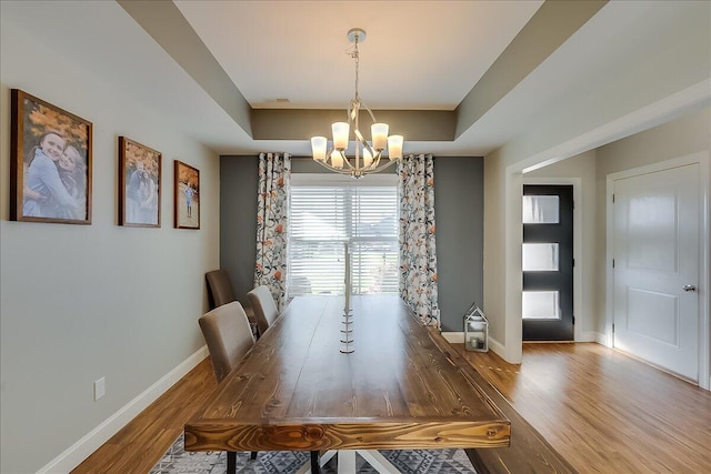 dining area featuring a chandelier, baseboards, and wood finished floors