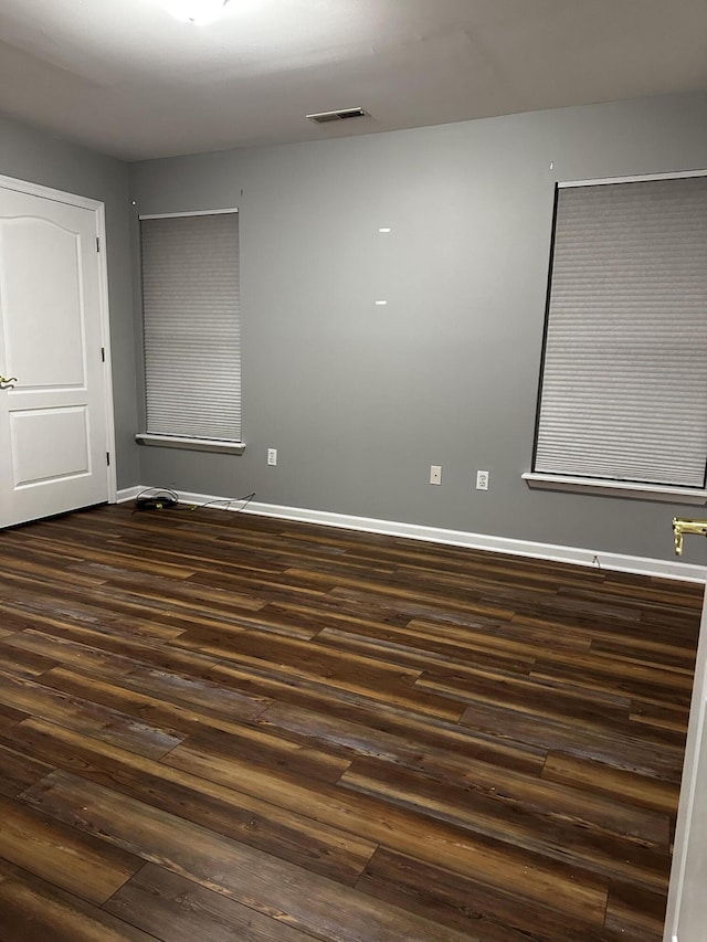 spare room featuring dark wood-type flooring and baseboards