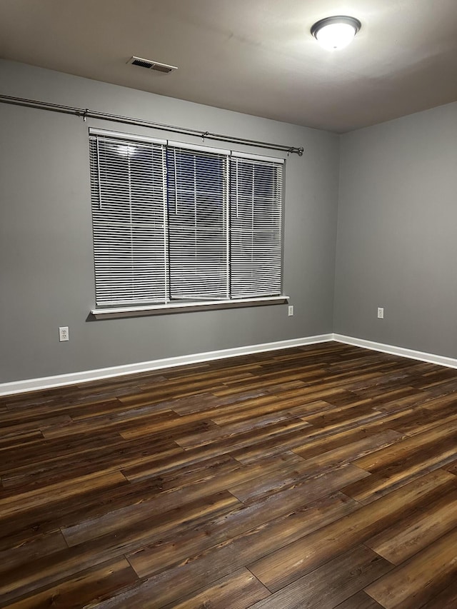 empty room with dark wood-style floors and baseboards