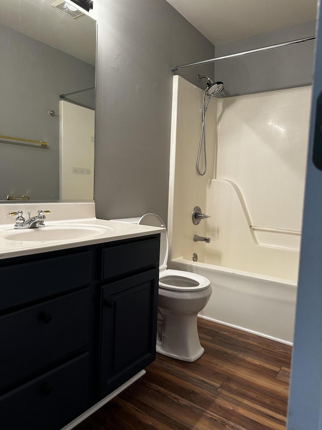 bathroom featuring wood finished floors, toilet, bathing tub / shower combination, and vanity