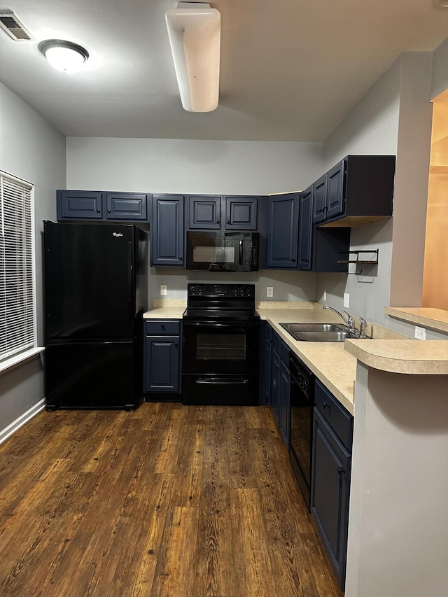 kitchen featuring black appliances, a sink, light countertops, and dark wood-type flooring