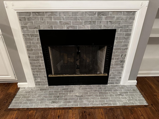 detailed view of a fireplace, baseboards, and wood finished floors