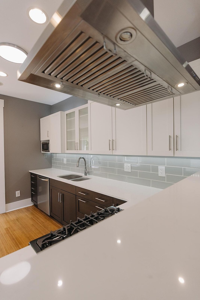 1010 Aurora Ave, Lexington, KY 40502 - kitchen featuring appliances with stainless steel finishes, a sink, range hood, light countertops, and white cabinetry