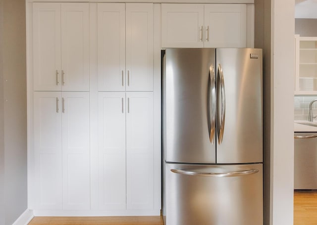 1010 Aurora Ave, Lexington, KY 40502 - kitchen featuring freestanding refrigerator, white cabinets, light wood-type flooring, baseboards, and a sink