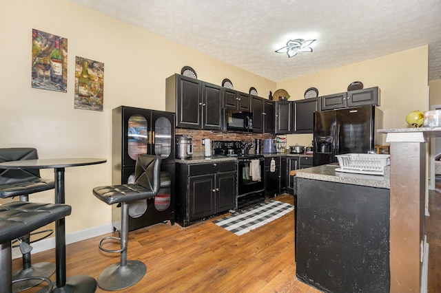 109 Rich Ln, Georgetown, KY 40324 - kitchen with black appliances, light wood finished floors, dark cabinets, light countertops, and a textured ceiling