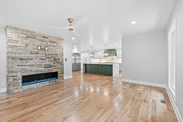 810 Cooper Dr, Lexington, KY 40502 - unfurnished living room with light wood-type flooring, baseboards, recessed lighting, ceiling fan, and a stone fireplace