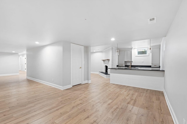 810 Cooper Dr, Lexington, KY 40502 - unfurnished living room featuring a brick fireplace, light wood-style floors, baseboards, recessed lighting, and a sink
