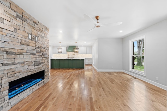 810 Cooper Dr, Lexington, KY 40502 - unfurnished living room featuring light wood finished floors, a fireplace, ceiling fan, a sink, and baseboards