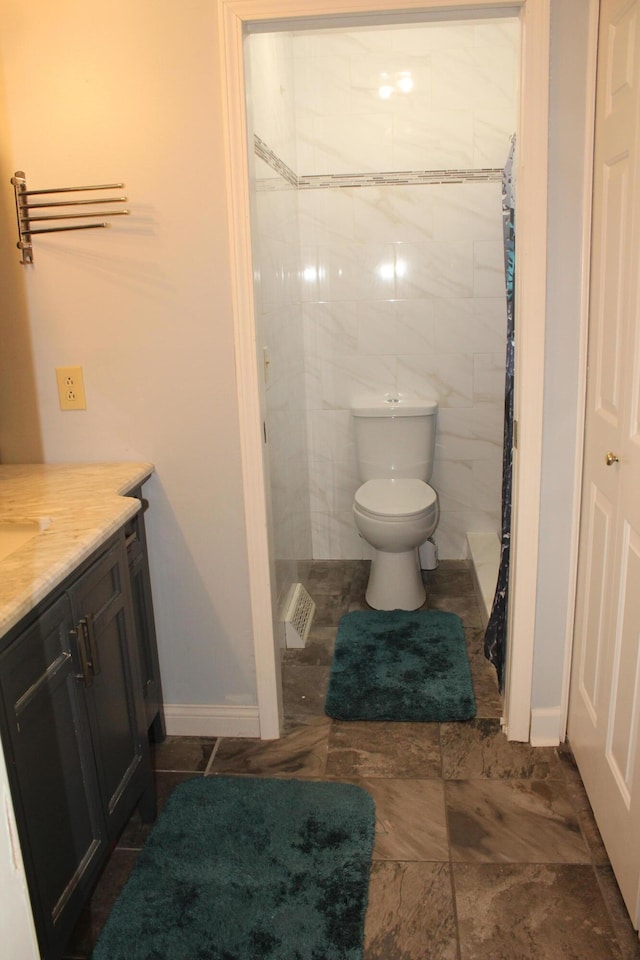 bathroom with toilet, vanity, curtained shower, and baseboards
