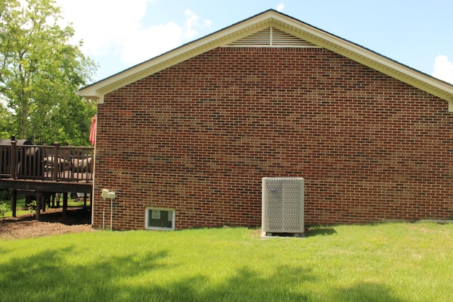 view of home's exterior with brick siding, a yard, and a deck