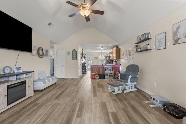 living area featuring a ceiling fan, light wood-type flooring, lofted ceiling, a chandelier, and baseboards
