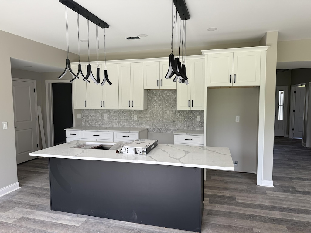 kitchen featuring white cabinetry, a center island, baseboards, and decorative backsplash