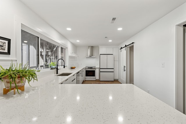 543 Laketower Dr Unit 140, Lexington, KY 40502 - kitchen featuring a sink, appliances with stainless steel finishes, wall chimney exhaust hood, a barn door, and white cabinets