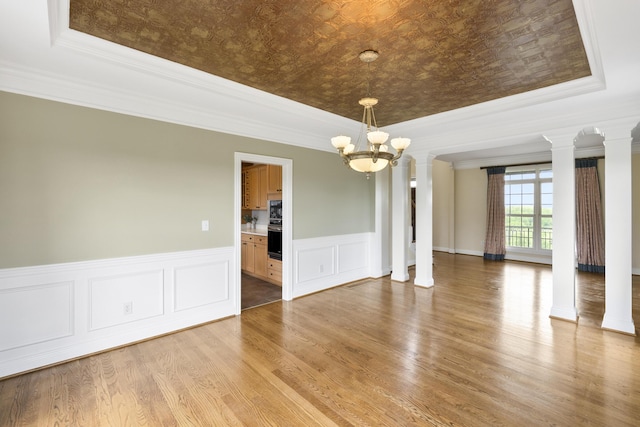 4301 Ravens Crest Ln, Lexington, KY 40515 - empty room featuring a tray ceiling, decorative columns, a chandelier, ornamental molding, and light wood-style flooring