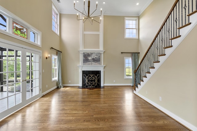 4301 Ravens Crest Ln, Lexington, KY 40515 - unfurnished living room with stairs, a chandelier, wood finished floors, a high ceiling, and ornamental molding