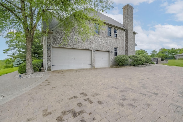 4301 Ravens Crest Ln, Lexington, KY 40515 - view of side of property featuring a chimney, decorative driveway, and an attached garage