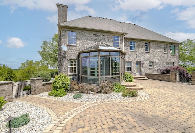4301 Ravens Crest Ln, Lexington, KY 40515 - back of property with a gate, a chimney, a sunroom, and brick siding