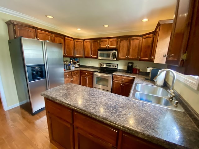 319 Huckleberry Ln, London, KY 40744 - kitchen featuring appliances with stainless steel finishes, a sink, a peninsula, dark countertops, and light wood-style flooring
