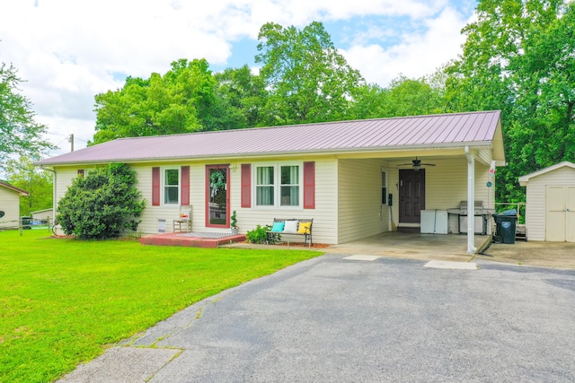 ranch-style home with a storage shed, a front lawn, ceiling fan, and metal roof