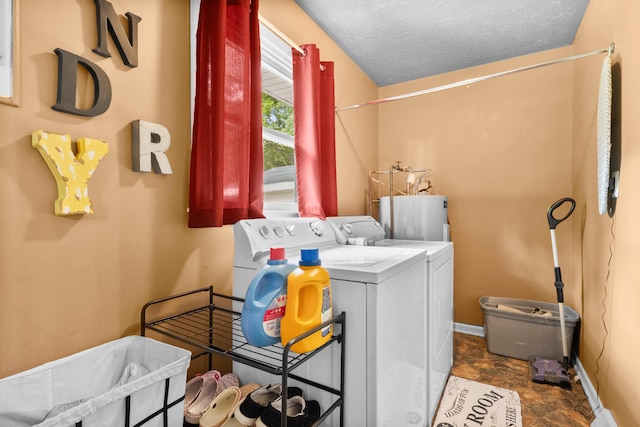 washroom featuring gas water heater, baseboards, washing machine and clothes dryer, stone finish floors, and a textured ceiling