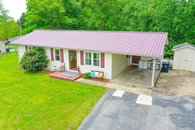 ranch-style house with asphalt driveway, a storage shed, a front lawn, metal roof, and an outbuilding