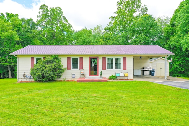 ranch-style home with a storage unit, a front lawn, an attached carport, an outbuilding, and asphalt driveway