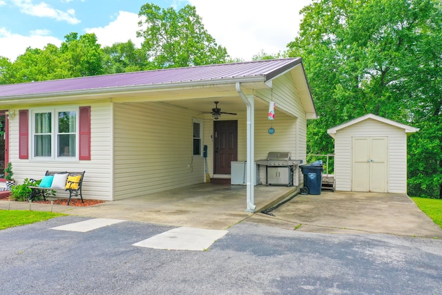 view of front facade featuring a storage shed, ceiling fan, an outdoor structure, metal roof, and a carport