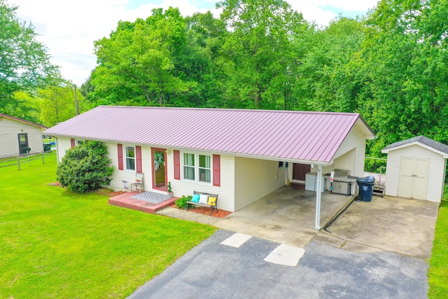 ranch-style home with asphalt driveway, a shed, a front lawn, metal roof, and an outbuilding