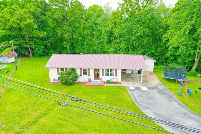 ranch-style house featuring driveway, an outbuilding, a carport, metal roof, and a trampoline