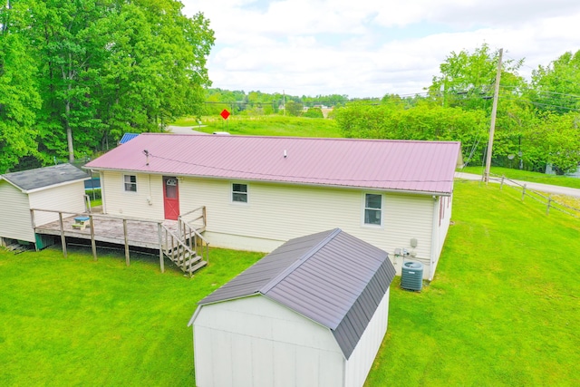 rear view of property featuring a lawn, an outdoor structure, metal roof, and a wooden deck