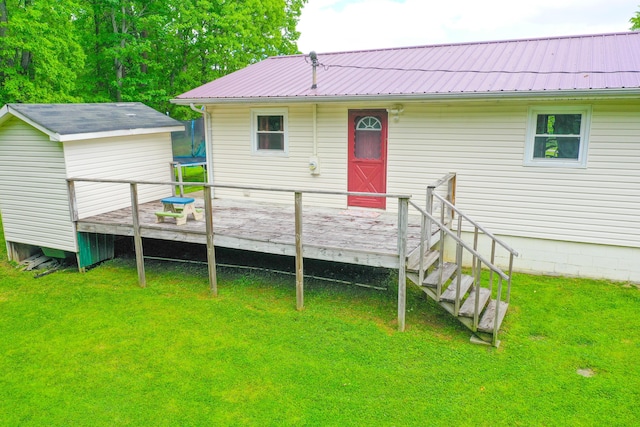 back of property featuring a wooden deck, a yard, and metal roof