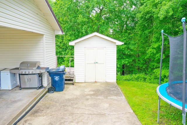 view of patio / terrace with a trampoline, a shed, an outdoor structure, and grilling area