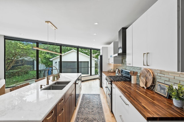 252 Cochran Rd, Lexington, KY 40502 - kitchen featuring wall chimney exhaust hood, a sink, butcher block counters, stainless steel appliances, and an island with sink